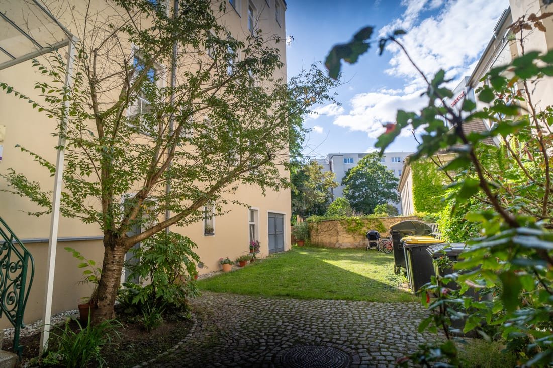 Begrünter Innenhof mit Baum und gepflastertem Weg